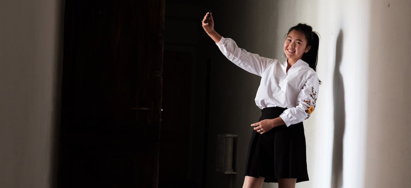 a girl holding a phone posing for a selfie smiling